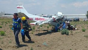Personal de Protección Civil camina junto a una aeronave accidentada en un terreno de cultivo en Puebla.