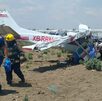 Personal de Protección Civil camina junto a una aeronave accidentada en un terreno de cultivo en Puebla.