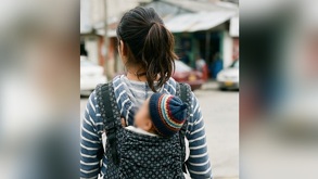 una adolescente cargando a un bebé en su espalda