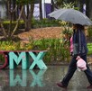 Una mujer se protege de las constantes precipitaciones registradas esta tarde en la capital.