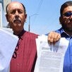 Dos hombres sostienen documentos en la mano correspondientes al fallo de un juicio.