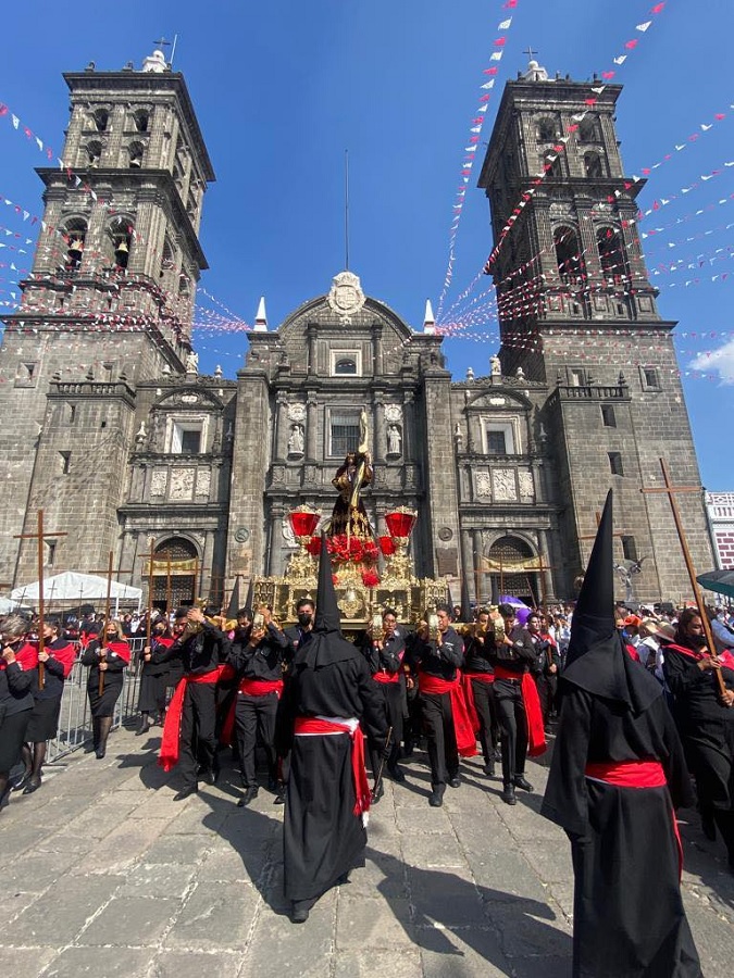 Personas uniformadas cargan la imagen de Jesucristo frente a la Catedral de Puebla, durante Semana Santa.
