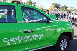 Patrulla color verde de Guardianes Viales de Zapopan con varios agentes formados en el fondo
