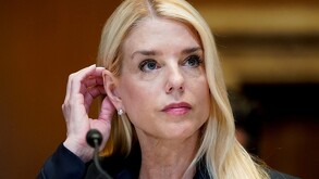Foto de primer plano de Pam Bondi, ex fiscal general de Estados Unidos, acomodándose el cabello detrás de la oreja, con un micrófono enfrente de ella.