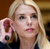 Foto de primer plano de Pam Bondi, ex fiscal general de Estados Unidos, acomodándose el cabello detrás de la oreja, con un micrófono enfrente de ella.