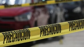 Cinta de policía rodeando un vehículo rojo.