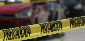 Cinta de policía rodeando un vehículo rojo.