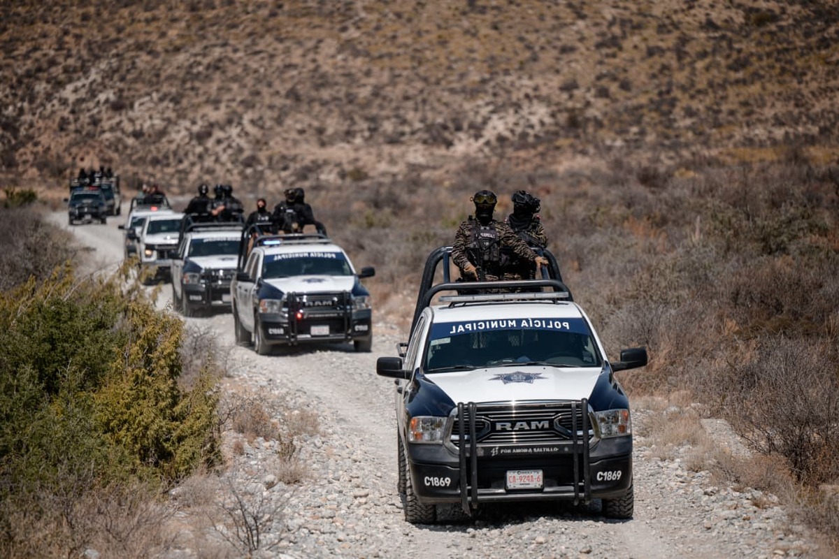 Elementos de la policía municipal realizan un operativo en convoy a bordo de patrullas tipo pickup sobre un camino de terracería en una zona rural de Coahuila.