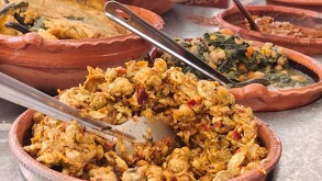 Se observan varios platillos con guisos de comida, están sobre una mesa.