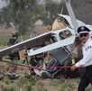 Policía camina junto a bomberos que realizan labores de rescate en una avioneta estrellada en Puebla.