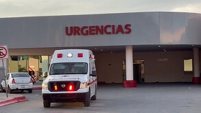 Se observa una ambulancia color blanco con rojo, está estacionada, afuera de un lugar que dice Urgencias.