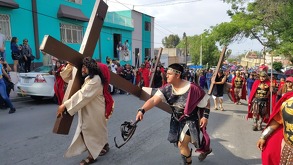 Un grupo de personas representa el viacrucis de Jesús por las calles de Saltillo, con actores caracterizados como soldados romanos y participantes cargando cruc