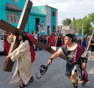 Un grupo de personas representa el viacrucis de Jesús por las calles de Saltillo, con actores caracterizados como soldados romanos y participantes cargando cruc