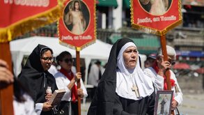 Monjas cargan banderas con la imagen de Jesucristo frente a la Catedral de Puebla.