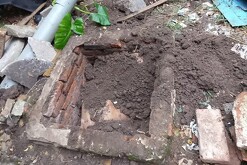 Pozo séptico cubierto por tierra esparcida alrededor con ladrillos, escombro y basura a los lados