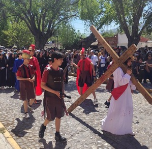 Imagen con efecto visual fragmentado de un recorrido al aire libre bajo árboles, donde se aprecia una escena relacionada con el viacrucis en Arteaga durante Sem