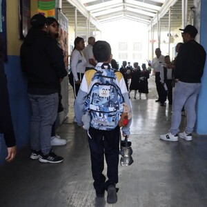 un niño con mochila entra caminando a su escuela