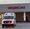 Se observa una ambulancia color blanco con rojo, está estacionada, afuera de un lugar que dice Urgencias.