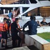Grupo de personas, salvavidas y policías de Puerto Vallarta reunidos a bordo y alrededor de un yate a la orilla de un puerto en Vallarta