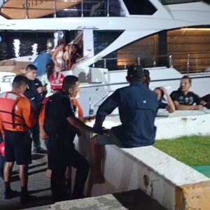Grupo de personas, salvavidas y policías de Puerto Vallarta reunidos a bordo y alrededor de un yate a la orilla de un puerto en Vallarta