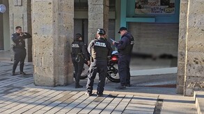 Cuatro oficiales de la Policía de Guadalajara y una moto patrulla delante del cuerpo de un hombre tendido en el suelo censurado con un blur