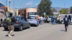 Civiles encapuchados con palos y piedras tomando un camión de Bonafont en medio de una carretera de Michoacán con autos alrededor