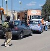Civiles encapuchados con palos y piedras tomando un camión de Bonafont en medio de una carretera de Michoacán con autos alrededor