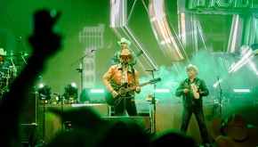Vocalista de Grupo Duelo interpreta uno de sus éxitos durante un concierto, acompañado de banda en vivo y ambiente festivo.