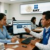 Contribuyente local (poblana, alrededor de 35 años) siendo asistida por un funcionario en una oficina del SAT, lo cual genera empatía y cercanía.