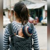 una adolescente cargando a un bebé en su espalda