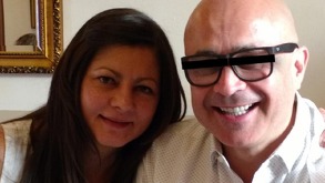 Pareja de esposos sonriendo para una fotografía; el hombre lleva una cinta negra en los ojos.