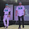 Se observa a dos hombres modelando unos uniformes color blanco con verde y letras que dicen SLW.