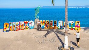 Turistas aprovechan la ocasión para tomarse una fotografía bajo el sol de la tarde en las emblemáticas letras de Puerto Vallarta frente al mar
