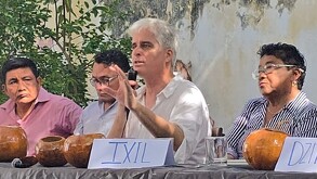 Ambientalista Sergio Oceransky sosteniendo un micrófono con una mano levantada mientras está sentado en una mesa con personas a los lados