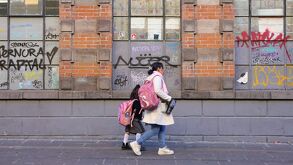 Mujer y una niña caminan junto a una escuela en Puebla.