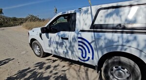 Camioneta del Instituto Jalisciense de Ciencias Forenses con una persona conduciendo sobre un camino de tierra y matorrales a los costados