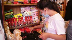 Niña con cubrebocas toma una bolsa de dulces con la mano.