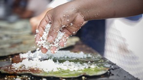 una persona coloca queso a una gordita en un comal