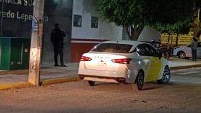 Vista de la parte de atrás de un taxi en Tonalá estacionado fuera de la Cruz Verde Pajaritos con un policía a un costado