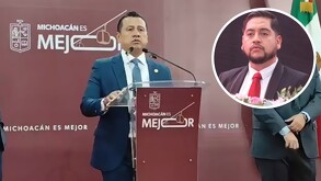 Fiscal de Michoacán, Carlos Torres Piña, delante de un podio con un micrófono durante conferencia de prensa con una foto del secretario de Ocampo a un lado