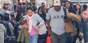 Personas adultas caminan mirando hacia abajo en una terminal de autobuses.