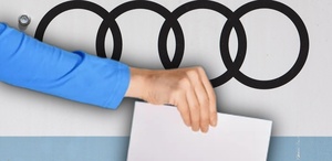 Mano sosteniendo un papel en una elección con el logo de Audi de fondo.