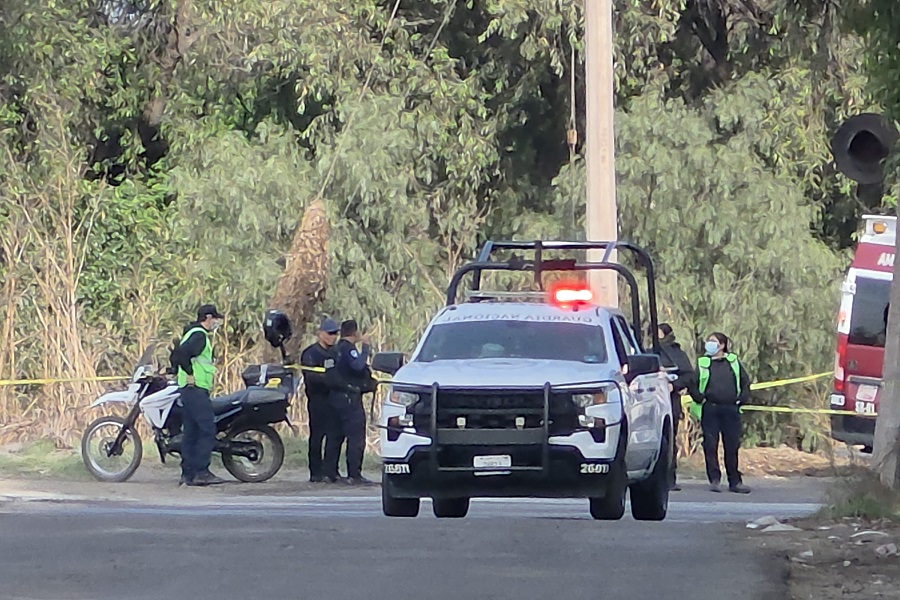 Policías al rededor de una patrulla en una zona acordonada con cinta de seguridad.