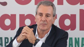 Hombre canoso de traje hace una mueca mientras mira hacia el frente.