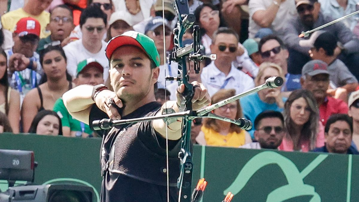 Hombre con gorra dispara una flecha con ayuda de un arco.