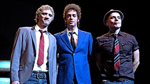 Integrantes de la banda de rock Soda Stereo, Charly Alberti, Gustavo Cerati y Zeta Bosio parados delante de un escenario