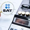 Mano sosteniendo una lupa con el logo del SAT delante de un documento con una calculadora, monedas y unos lentes a un lado