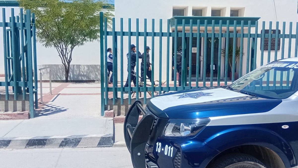 Edificio blanco con rejas verdes y patrulla de Gómez Palacio