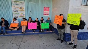 Padres de familia con carteles manifestándose al exterior de la escuela primaria Encarnación Rosas en Guadalajara
