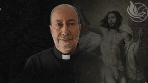 Se observa a un hombre con atuendo de padre, en un fondo negro y con la imagen de Jesús atrás.